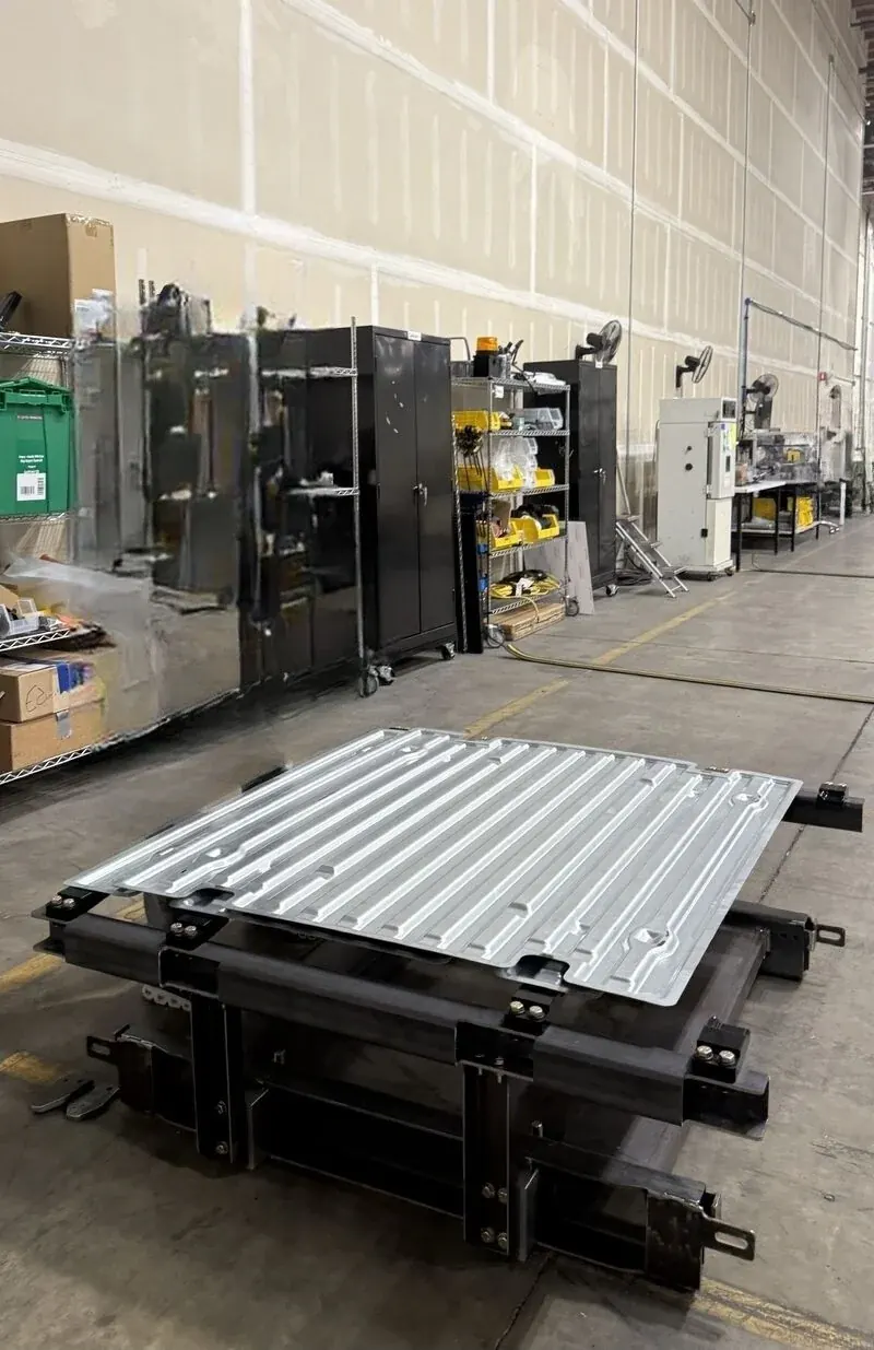 Single-piece stamped steel pallet tray on its test fixture